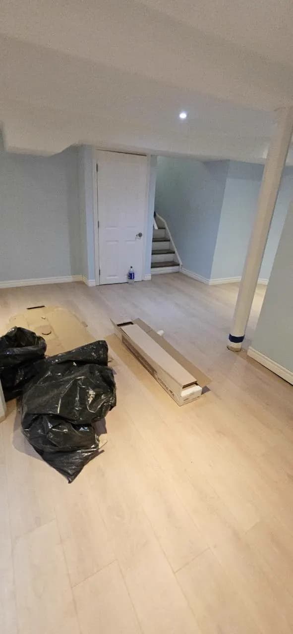 Bright basement room with newly installed light-coloured flooring