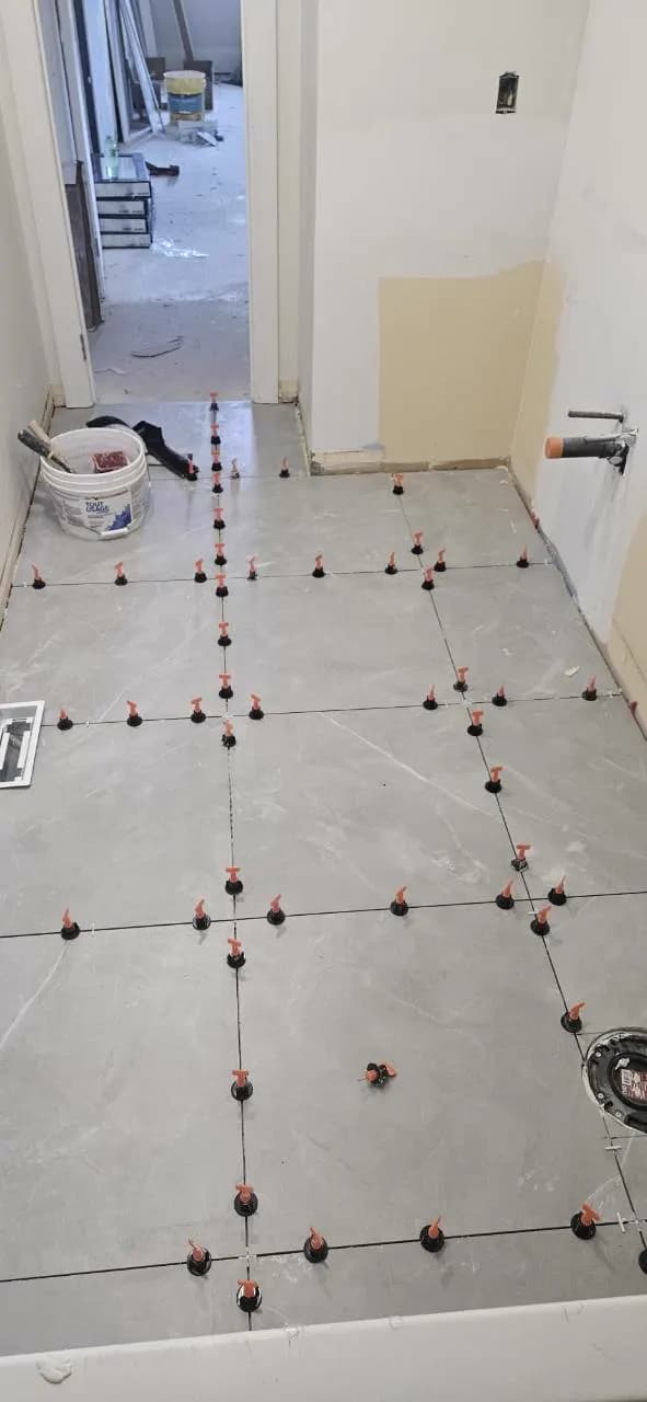 Large-format grey bathroom floor tile aligned with levelling clips