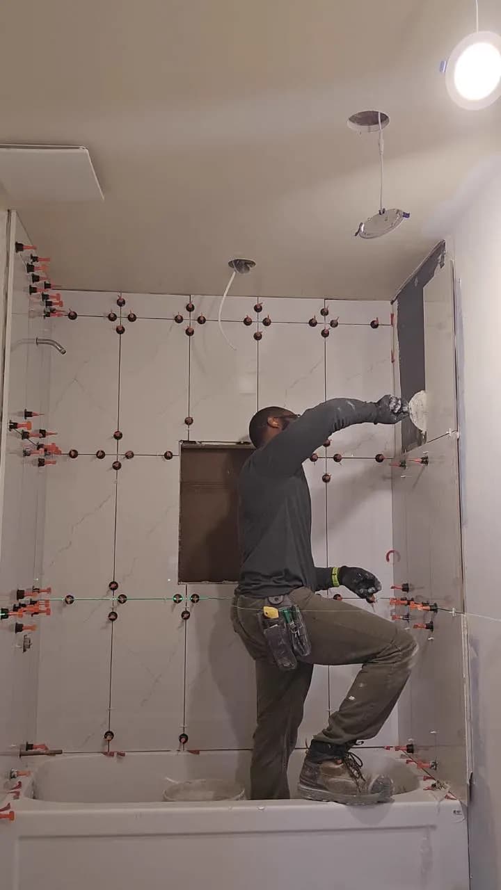 JBC renovation team member installing large-format bathroom wall tile