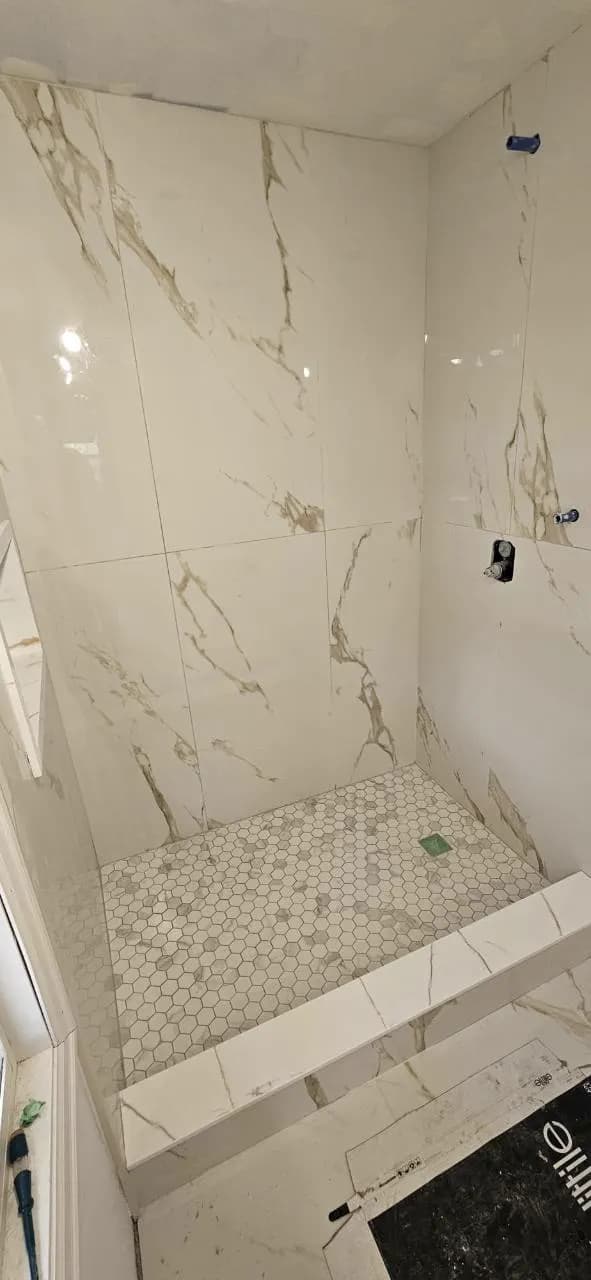 Walk-in shower with marble-look wall tile and hexagonal mosaic floor tile